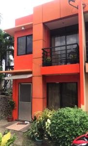 道伊斯的住宿－2BR 2BT home with pool between Tagbilaran and Panglao，一座红色的建筑,前面有植物