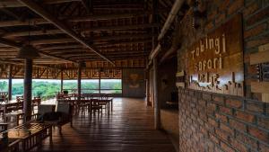 Tabingi Safari Cottages في Katunguru: مطعم بطاولات وكراسي وجدار من الطوب