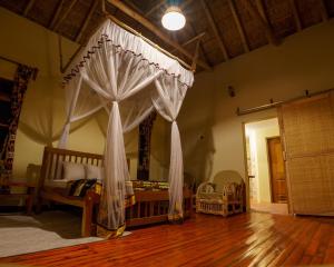 a bedroom with a canopy bed and a wooden floor at Tabingi Safari Cottages in Katunguru