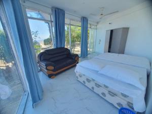 ein Schlafzimmer mit einem Bett, einem Stuhl und einem Fenster in der Unterkunft Atlantic Resort in Jaliapāra