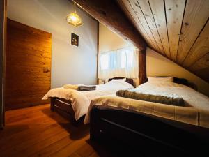 1 Schlafzimmer mit 2 Betten und Holzdecke in der Unterkunft Yufuin Log House no Yado Tom Sawyer in Yufu