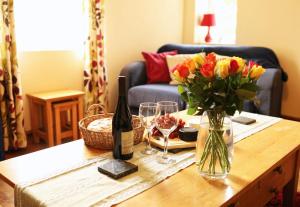 a table with a vase of flowers and a bottle of wine at Pet-Friendly Logburner Horse Stable Views in Hay-on-Wye