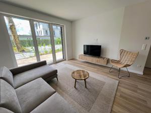 een woonkamer met een bank, een tv en een stoel bij Apartman in Platan Garden in Balatonboglár