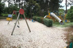 ein Park mit einem Spielplatz mit Rutsche in der Unterkunft Logement entier : appartement en résidence - Lacanau, France in Lacanau