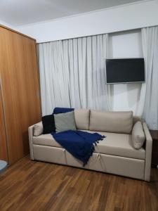 a living room with a couch and a television at Hotel Slavieiro Moema Suite Prime Familia in Sao Paulo