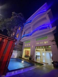 a large white building with a swimming pool at night at Centro Guest House in Siem Reap