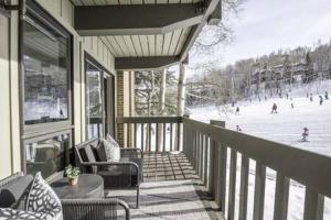 a porch of a house with skiers on a ski slope at Renovated 2 BR Condo w Hot Tub -Mountain Views! in Snowmass Village
