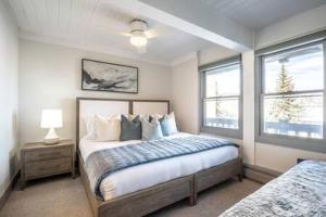 a bedroom with a bed and two windows at Renovated 2 BR Condo w Hot Tub -Mountain Views! in Snowmass Village