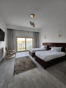 um quarto de hotel com duas camas e uma grande janela em NUB INN em Aswan