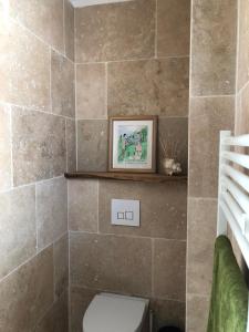 a bathroom with a toilet and a tile wall at La Figuière in Manosque