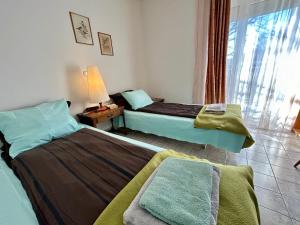 two beds in a hotel room with a window at Pansion Vila Vanda Vukovar in Vukovar