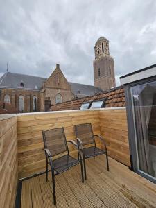 2 sillas sentadas en una terraza con una valla de madera en Drostenstraat (voor groepen), en Zwolle