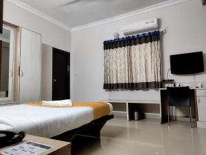 a bedroom with a bed and a desk and a television at Hotel Luxor Park in Hyderabad