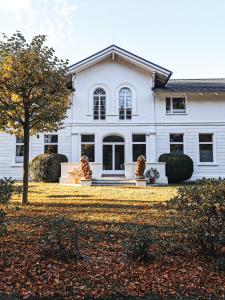 Una casa blanca con dos estatuas delante. en Hotel Weißes Schloß, en Heringsdorf