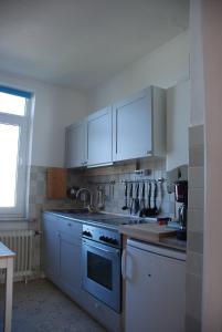 a kitchen with white cabinets and a sink and a stove at Haus Sonnensegler Ferienwohnung Luv in Cuxhaven