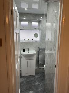 La salle de bains est pourvue d'un lavabo blanc et d'un miroir. dans l'établissement Cosy Corner - 2 beds, free parking, garden, 2 mins walk to Southampton General Hospital, à Southampton
