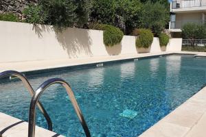una piscina con acqua blu accanto a un edificio di Appartement 2 pers, terrasse, piscine, parking a Saint-Rémy-de-Provence