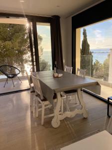 une table à manger avec des chaises blanches et une grande fenêtre dans l'établissement Veuràs el Mar - Madrague Beach apartment 15, à Roses