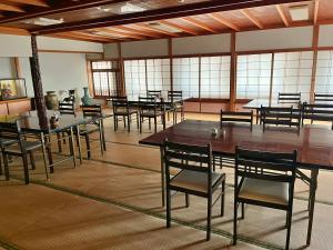 Kanko Ryokan Yamato في Ikoma: غرفة كبيرة بها طاولات وكراسي ونوافذ