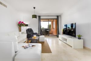 uma sala de estar com um sofá branco e uma televisão em Casares Costa Gem: 2BR with Pool em Bahia de Casares