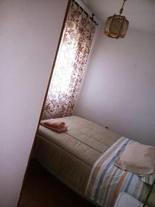 Cama pequeña en habitación con ventana en Casa en Pinilla de Buitrago, en Gargantilla del Lozoya