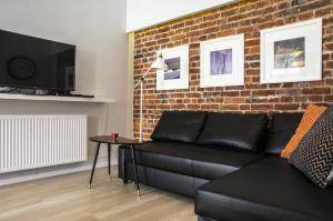 a living room with a black couch and a brick wall at Apartament Conces II in Wrocław
