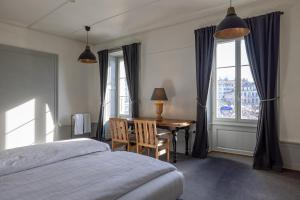 a bedroom with a desk and a bed and a window at Vevey Hotel & Guesthouse in Vevey