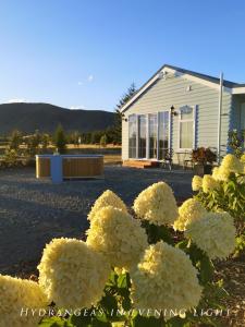 a bush of white flowers in front of a house at Kahurangi Cottage Twizel in Twizel