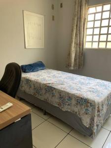 a bedroom with a bed and a desk and a window at Elegância e Espaço. Casa Grande Individual in Palmas