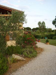 un jardín con flores rojas y una casa en Casa Le Basse - Giuncarico, en Gavorrano