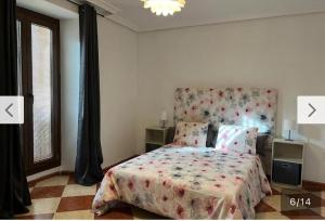 巴埃薩的住宿－VIVIENDA TURISTICA LA CASA DE BAEZA，一间卧室配有一张带花卉床头板和窗户的床。
