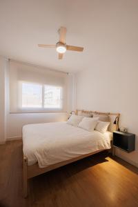 a white bedroom with a bed and a ceiling fan at Atico duplex Playa Area barcelona con SPA exterior in Montgat