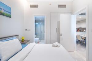 a white bedroom with a bed and a bathroom at SuperHost - Comfort 1BR Centurion Onyx Retreat with Balcony in Dubai