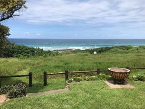 un banco sentado en el césped cerca del océano en Scottburgh beach house, en Scottburgh