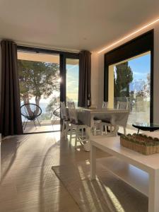 - un salon avec une table blanche, des chaises et des fenêtres dans l'établissement Veuràs el Mar - Madrague Beach apartment 15, à Roses