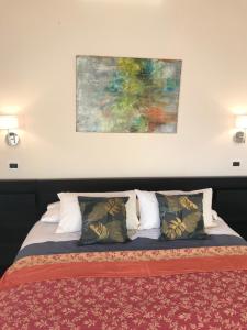 una cama con almohadas y una pintura en la pared en Villa Marlene B&B, en Albenga