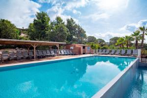 a swimming pool with chairs and a pavilion at Résidence Les Hameaux de Santa Giulia in Porto-Vecchio