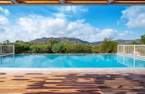a swimming pool with mountains in the background at Résidence Les Hameaux de Santa Giulia in Porto-Vecchio