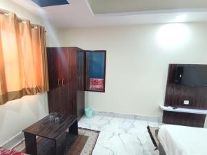hotel nanda inn في حاريدوار: غرفة بسرير وطاولة وتلفزيون