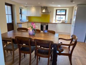 a kitchen with a wooden table with chairs and a vase with flowers at Traditional Welsh cottage in Llanberis in Llanberis