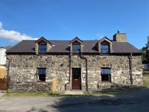 an old stone house with a black roof at Traditional Welsh cottage in Llanberis in Llanberis