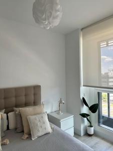 a white bedroom with a bed and a window at Apartamento Torre Australis in Madrid