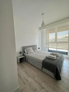 a white bedroom with a bed and a window at Apartamento Torre Australis in Madrid