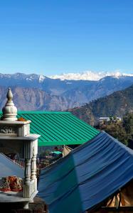 a building with a green roof with mountains in the background at KASANA CLUB MUSSOORIE in Mussoorie