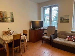 a living room with a couch a table and a tv at Apartament Chopina 2 in Węgorzewo