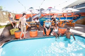eine Gruppe von Menschen, die um einen Pool herum sitzen in der Unterkunft Never at Home Green Point in Kapstadt