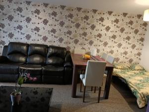 a living room with a table and a leather couch at Stylish 2BD near Gatwick Airport in Crawley in Crawley