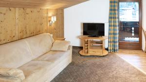 sala de estar con sofá y TV en Appartements Alpenrose, en Längenfeld