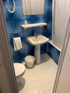 uma casa de banho em azulejos azuis com um WC e um lavatório em Hôtel Ambassadeur em Paris