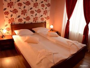 1 dormitorio con 1 cama grande con sábanas blancas y almohadas en Anastasija Sobe AS, en Vrnjačka Banja